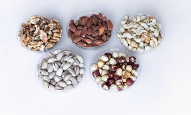 Sağlıklı yiyecekler. Somunlar beyaz gri masa üstü görünümünde çeşitli karıştırın. Arka plan görüntüsü için farklı baklagiller koleksiyonu yakın fındık, antep fıstığı, badem, kaju fıstığı, fıstık, ceviz. Görüntü