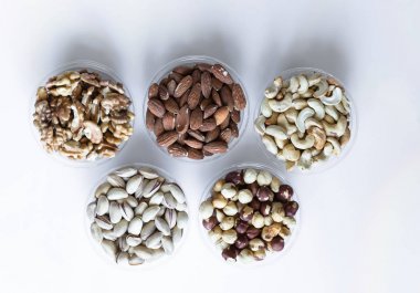 Sağlıklı yiyecekler. Somunlar beyaz gri masa üstü görünümünde çeşitli karıştırın. Arka plan görüntüsü için farklı baklagiller koleksiyonu yakın fındık, antep fıstığı, badem, kaju fıstığı, fıstık, ceviz. Görüntü