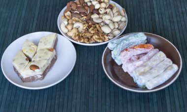 Geleneksel Türk Lokumu. Bir tabakta oryantal tatlı helvası. Arka planda izole edilmiş. Doğu lezzetleri. Sağlıklı yiyecekler. Fındık karışımı çeşitleri. Görüntü için farklı baklagiller koleksiyonu yakın fındık, antep fıstığı, badem, kaju fıstığı, fıstık, wal