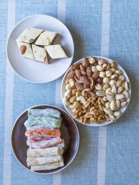 Geleneksel Türk Lokumu. Bir tabakta oryantal tatlı helvası. Arka planda izole edilmiş. Doğu lezzetleri. Sağlıklı yiyecekler. Fındık karışımı çeşitleri. Görüntü için farklı baklagiller koleksiyonu yakın fındık, antep fıstığı, badem, kaju fıstığı, fıstık, wal