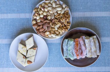 Geleneksel Türk Lokumu. Bir tabakta oryantal tatlı helvası. Arka planda izole edilmiş. Doğu lezzetleri. Sağlıklı yiyecekler. Fındık karışımı çeşitleri. Görüntü için farklı baklagiller koleksiyonu yakın fındık, antep fıstığı, badem, kaju fıstığı, fıstık, wal
