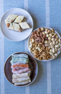 Geleneksel Türk Lokumu. Bir tabakta oryantal tatlı helvası. Arka planda izole edilmiş. Doğu lezzetleri. Sağlıklı yiyecekler. Fındık karışımı çeşitleri. Görüntü için farklı baklagiller koleksiyonu yakın fındık, antep fıstığı, badem, kaju fıstığı, fıstık, wal