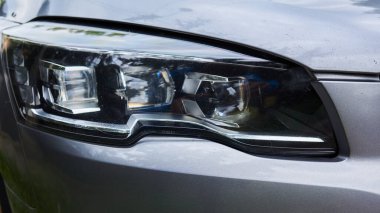 Bir arabanın farları siyahtır. Araba park halinde.