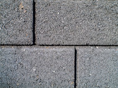 Üzerinde gri tuğla olan gri bir duvar. Tuğla gri ve üzerinde siyah bir çizgi var.