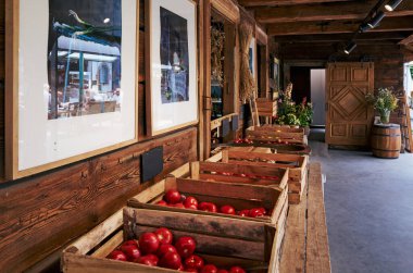 Üzerinde kırmızı domates sandıkları olan ahşap bir masa. Sandıklar sıraya dizilir ve domatesler ön planda görünür. Sahnenin ahşap sandıklarla kırsal ve doğal bir havası var.