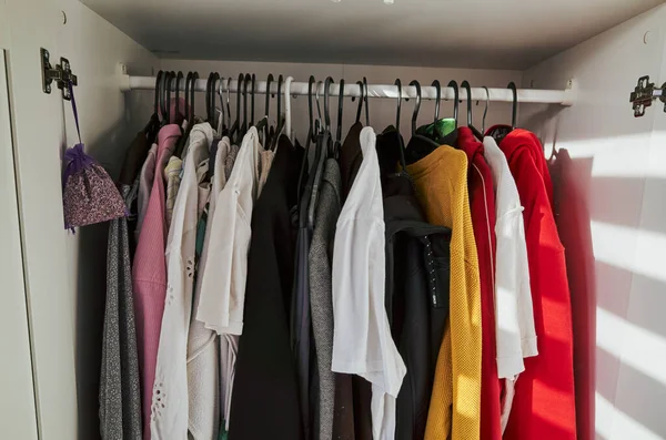 Dolabın sol tarafında beyaz bir gömlek ve sağ tarafında da kırmızı bir gömlek asılı.