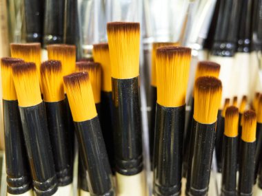 Siyah saplı ve sarı tüylü bir sürü fırça. Bazı fırçalar siyah ve sarı, diğerleri siyah ve kahverengidir.