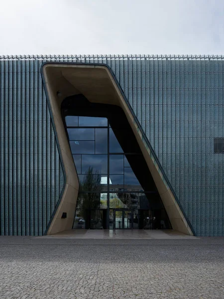 Binanın çok modern ve şık bir tasarımı var. Giriş, binaya açıklık ve şeffaflık hissi veren büyük cam bir pencereden oluşuyor. Bina bir şehirde yer almaktadır. Varşova 15.04.2025, Polonya