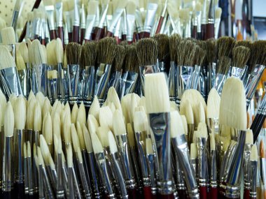 Büyük bir boya fırçası koleksiyonu bir mağazada sergilenir. Bir sürü farklı boyut ve renk var.