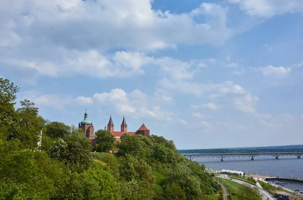 Arkasında bir köprü ve kilise olan güzel bir şehir manzarası. Gökyüzü açık ve güneş parlıyor.