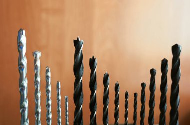 Sıraya dizilmiş ahşap ve metal için çeşitli matkap uçları, inşaat ve onarım işleri için farklı boyutları ve araçları gösteriyor.