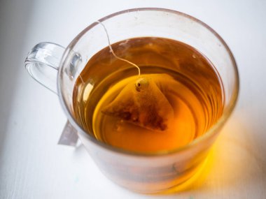 İçinde çay poşeti yüzen bir fincan çay. Çay poşeti küçük, ince bir parça kağıttan yapılmıştır.