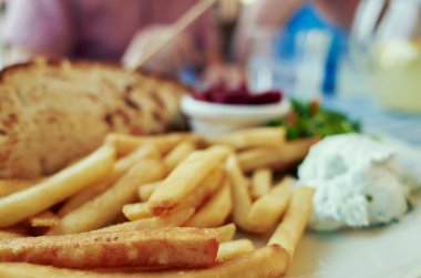 Plate of french fries and a sandwich. The sandwich is on the left side of the plate and the fries are on the right