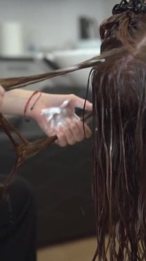 Kremalı kıvırcık saçlar. Profesyonel bir kuaförün ellerindeki doğal bukleler. Kıvırcık kız yöntemi.