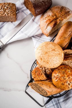 Taze ev yapımı tahıl ekmeği, bir metal sepet, beyaz mermer arka plan kopya alanı içinde çeşitli