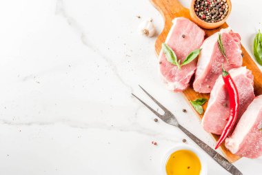 Çiğ et, domuz biftek baharatlar, otlar, zeytinyağı, beyaz mermer zemin kesme tahtası, üstten görünüm, kopya alanı ile