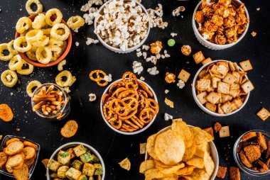 Varyasyon farklı sağlıksız atıştırmalıklar kraker, tatlı tuzlu popcorn, ekmeği, fındık, payet, bretsels, arka kara tahta kopya alanı