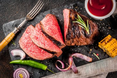 Taze ızgara sığır eti, ev yapımı barbekü et orta pişmiş ile baharat, koyu arka plan, siyah taş kesme tahtası üzerinde alan yukarıdaki kopyalama