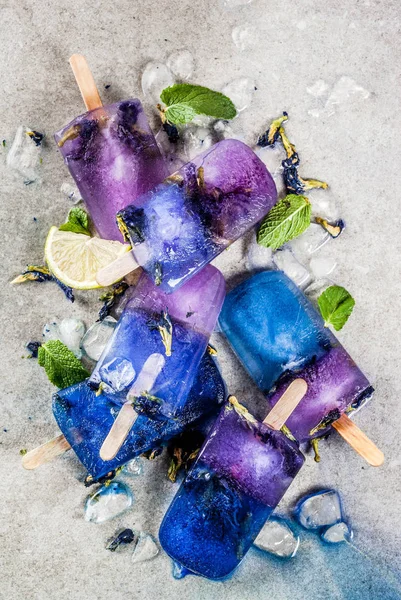 当然のことながら有機夏のお菓子 蝶エンドウ豆花茶 灰色コンクリート背景の青と紫の自家製アイス クリーム アイスキャンディー コピー スペース — ストック写真