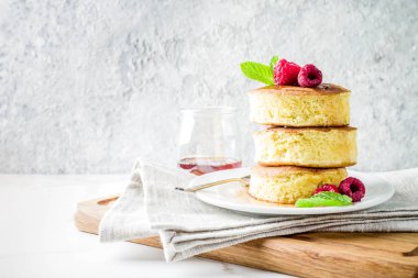 Trendy Asya gıda, kabarık Japonya sufle krep, hotcakes akçaağaç şurubu ve ahududu açık beton arka planı ile alanı Kopyala