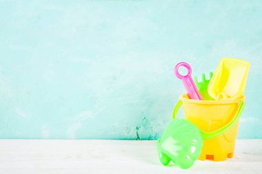 Yaz tatil konseptiyle plastik mavi tekne, lifebuoy ve parlak kum oyuncakları, kopya alanı