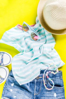 Yaz tatil kavramı, yaz çocuk bezi seti - çocuklar şort, tişört, şapka, güneş gözlüğü, bilezik kolye, spor ayakkabıları, parlak sarı arka plan düz yatıyordu kopya alanı üstüne