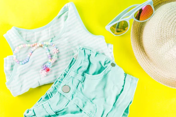 Yaz tatil kavramı, yaz çocuk bezi seti - çocuklar şort, tişört, şapka, güneş gözlüğü, bilezik kolye, spor ayakkabıları, parlak sarı arka plan düz yatıyordu kopya alanı üstüne