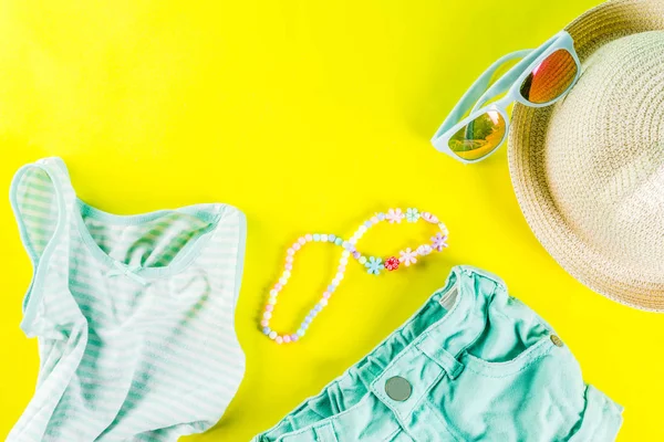Yaz tatil kavramı, yaz çocuk bezi seti - çocuklar şort, tişört, şapka, güneş gözlüğü, bilezik kolye, spor ayakkabıları, parlak sarı arka plan düz yatıyordu kopya alanı üstüne