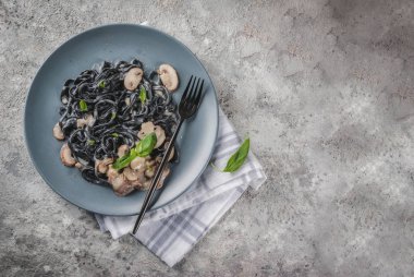 Modern İtalyan yemeği, Akdeniz yemekleri, siyah mürekkep balığı mürekkep spagetti makarna champignon mantar, zeytin yağı ve fesleğen, üstünde gri Taş Masa üstü görüş alanı Kopyala