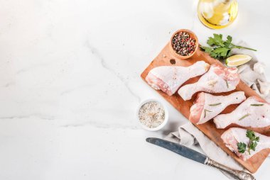 Çiğ et, tavuk budu, zeytin yağı, otlar ve Baharatlar, beyaz mermer arka planda, alan üst görünüm Kopyala
