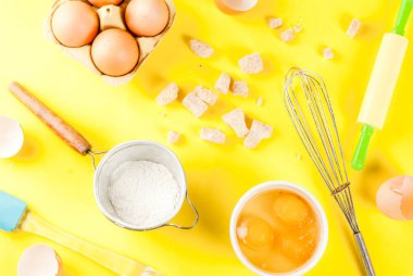 Malzemeler ve yemek pişirmek için kaplar pişirme yumurta, un, şeker, çırpma, oklava, parlak sarı arka plan üzerinde Üstten Görünüm