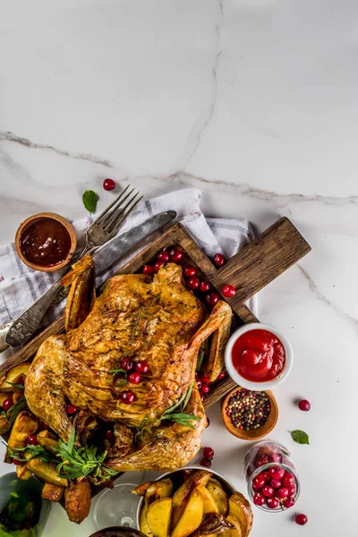 Christmas, thanksgiving food, baked roasted chicken with cranberry and herbs, served with fried vegetables, fresh berries wine and sauces on white marble table, copy space top view