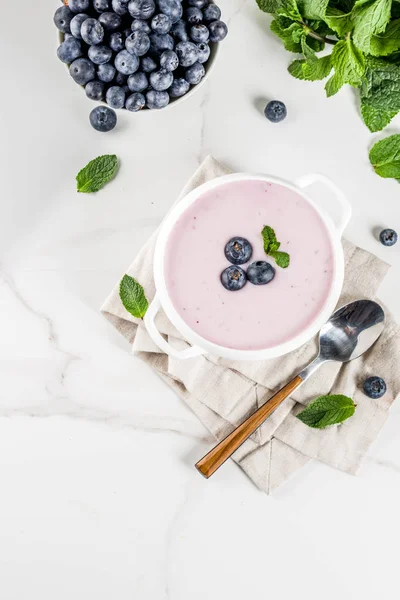 Sweet creamy blueberry soup, vegan summer food, white marble background copy space