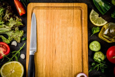 Yemek arka plan, taze salata malzemeleri, İtalyan mutfağı - Domates, zeytin yağı, limon, salatalık, roka, maydanoz, soğan, bıçak ve kesme tahtası, karanlık paslı arka plan kopya alanı üstten görünüm