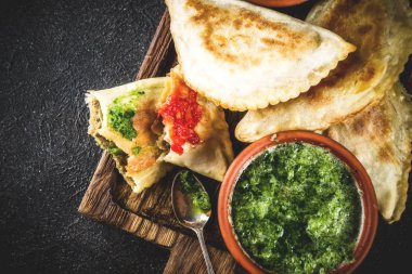 Latin Amerika, Meksika, Şili gıda. Geleneksel pişmiş pasta empanadas ile sığır eti, iki baharatlı soslar, karanlık paslı arka plan boşluk kopyalama