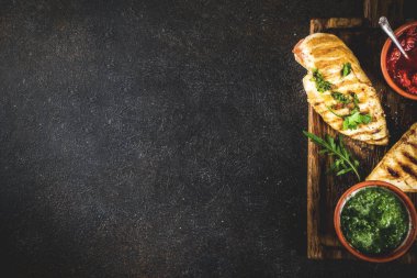 Izgara tavuk göğsü ile baharatlı sos, domates ve otlar üzerinde karanlık paslı arka plan kopya alanı üstten görünüm