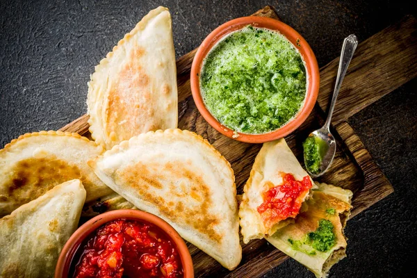 Latin Amerika, Meksika, Şili gıda. Geleneksel pişmiş pasta empanadas ile sığır eti, iki baharatlı soslar, karanlık paslı arka plan boşluk kopyalama