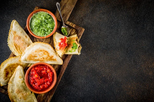 Latin Amerika, Meksika, Şili gıda. Geleneksel pişmiş pasta empanadas ile sığır eti, iki baharatlı soslar, karanlık paslı arka plan boşluk kopyalama