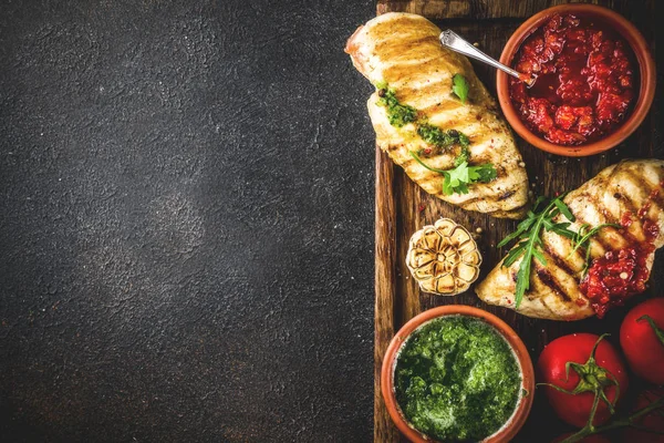 Izgara tavuk göğsü ile baharatlı sos, domates ve otlar üzerinde karanlık paslı arka plan kopya alanı üstten görünüm