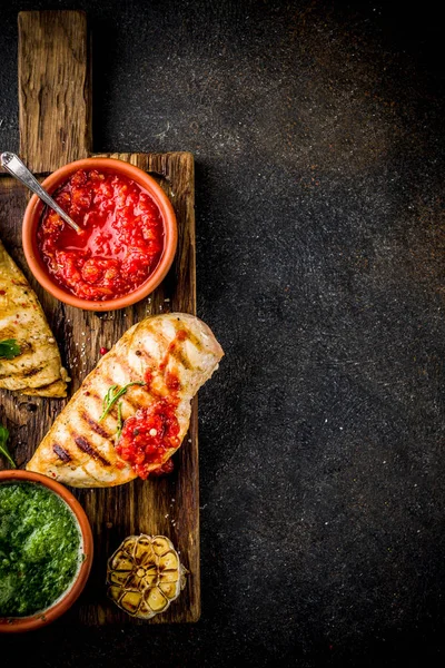 Izgara tavuk göğsü ile baharatlı sos, domates ve otlar üzerinde karanlık paslı arka plan kopya alanı üstten görünüm