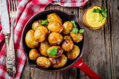 Fırında kızartma tavası bütün genç patates, ev yapımı Vejetaryen yiyecekler, eski ahşap rustik masa, soslu, alan üst görünüm Kopyala