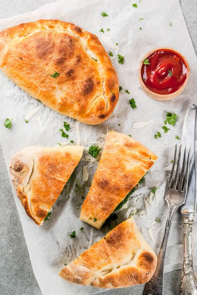 İtalyan gıda, ıspanak ve peynir, gri taş zemin, kapalı pizza calzone kopyalama alanı Üstten Görünüm