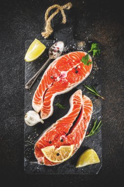 Çiğ Somon Balık biftek ile limon, otlar, zeytin yağı, ızgara, kayrak kesme tahtası, karanlık paslı arka plan kopya alanı için hazır