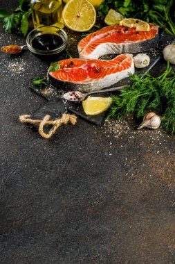 Çiğ Somon Balık biftek ile limon, otlar, zeytin yağı, ızgara, kayrak kesme tahtası, karanlık paslı arka plan kopya alanı için hazır