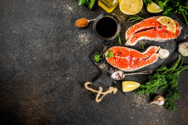 Çiğ Somon Balık biftek ile limon, otlar, zeytin yağı, ızgara, kayrak kesme tahtası, karanlık paslı arka plan kopya alanı için hazır