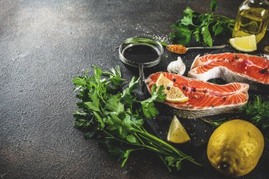 Çiğ Somon Balık biftek ile limon, otlar, zeytin yağı, ızgara, kayrak kesme tahtası, karanlık paslı arka plan kopya alanı için hazır