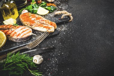 Izgara Somon Balık biftek malzemeler limon, otlar, zeytin yağı, kayrak kesme tahtası, karanlık paslı arka plan kopya alanı ile