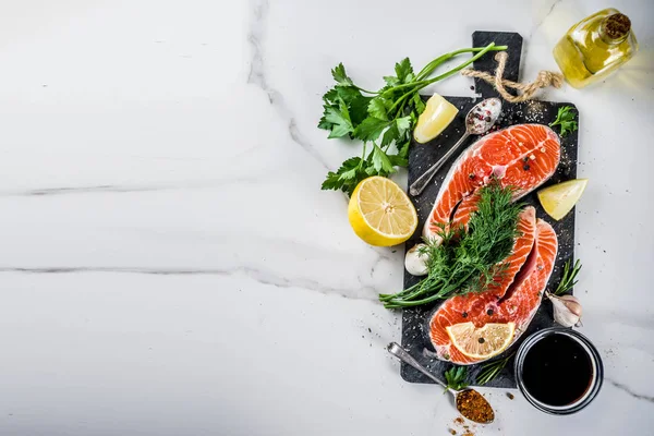 Biftek ile limon, otlar, zeytin yağı, ızgara, kayrak kesme tahtası, beyaz mermer zemin kopya alanı yukarıdaki için hazır çiğ Somon Balık
