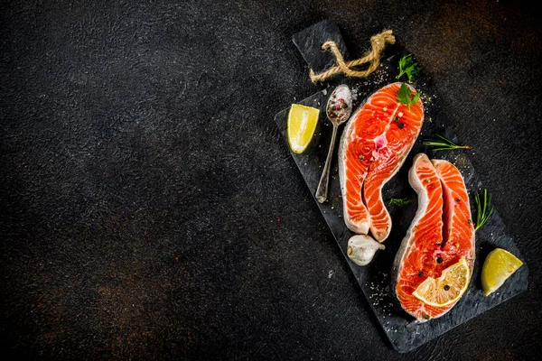 Çiğ Somon Balık biftek ile limon, otlar, zeytin yağı, ızgara, kayrak kesme tahtası, karanlık paslı arka plan kopya alanı için hazır