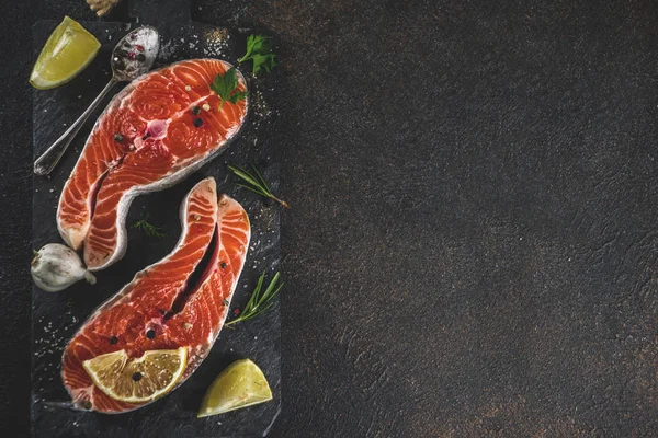Çiğ Somon Balık biftek ile limon, otlar, zeytin yağı, ızgara, kayrak kesme tahtası, karanlık paslı arka plan kopya alanı için hazır